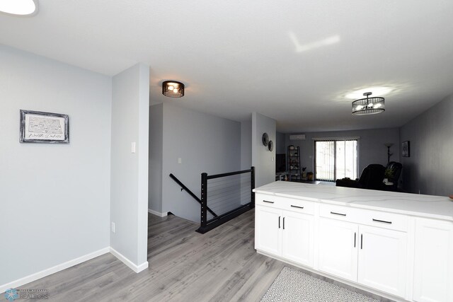 kitchen featuring light stone counters, light wood finished floors, white cabinetry, and baseboards