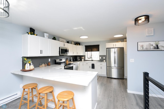 kitchen featuring decorative backsplash, a peninsula, white cabinetry, and stainless steel appliances