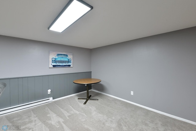 interior space with a baseboard radiator, baseboards, carpet, and a wainscoted wall