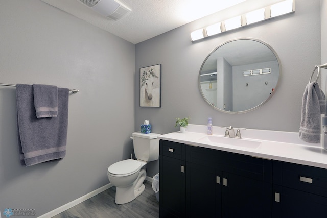 bathroom featuring vanity, wood finished floors, baseboards, a textured ceiling, and toilet