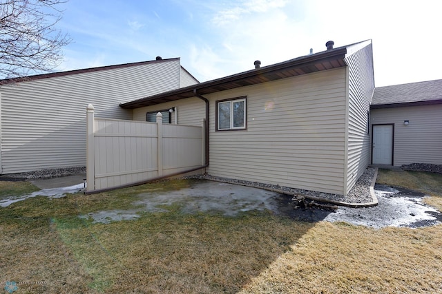 rear view of property featuring a lawn and fence