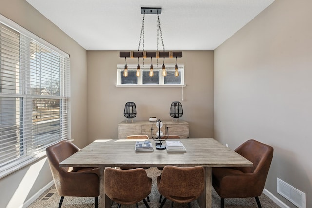 carpeted dining space featuring visible vents and baseboards