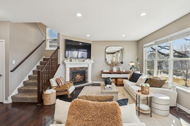 living area with stairway, wood finished floors, baseboards, a fireplace, and recessed lighting