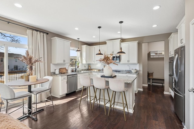 kitchen with dark wood-type flooring, a kitchen island, recessed lighting, appliances with stainless steel finishes, and white cabinets