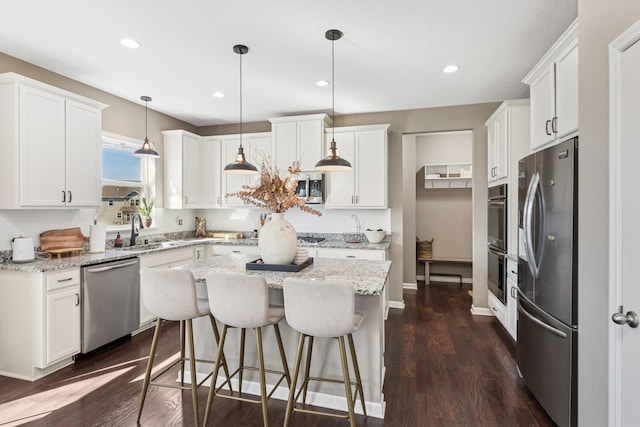 kitchen featuring a sink, a center island, white cabinetry, stainless steel appliances, and dark wood-style flooring