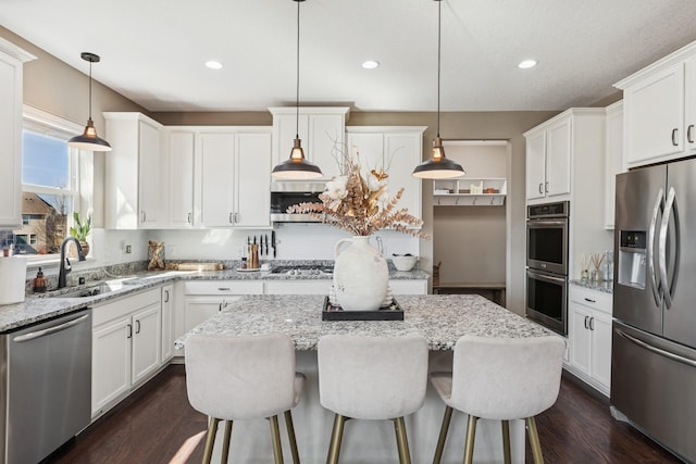 kitchen featuring a sink, stainless steel appliances, dark wood-type flooring, white cabinets, and a center island