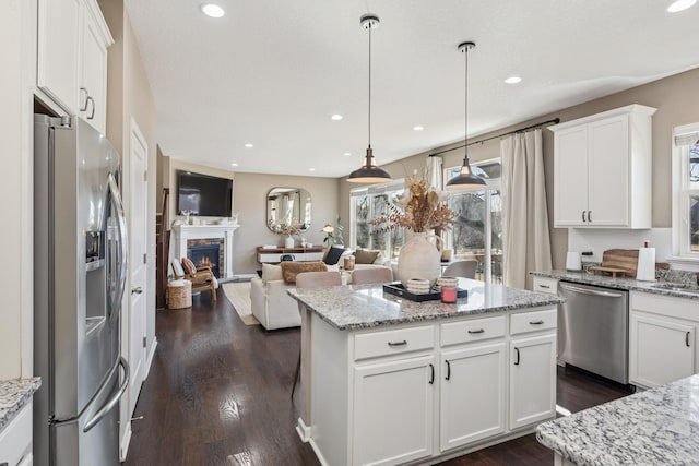 kitchen featuring a fireplace, dark wood-type flooring, white cabinets, appliances with stainless steel finishes, and open floor plan