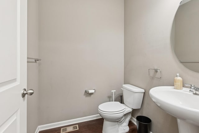 half bathroom with visible vents, toilet, baseboards, and a sink