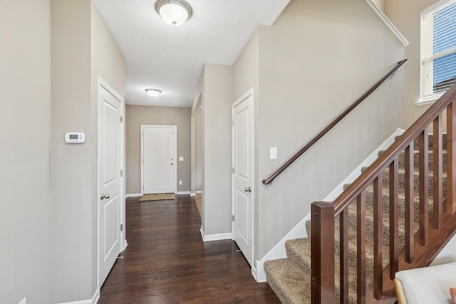 hallway with wood finished floors, baseboards, and a textured ceiling