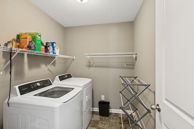 clothes washing area featuring washer and dryer, baseboards, a textured ceiling, and laundry area