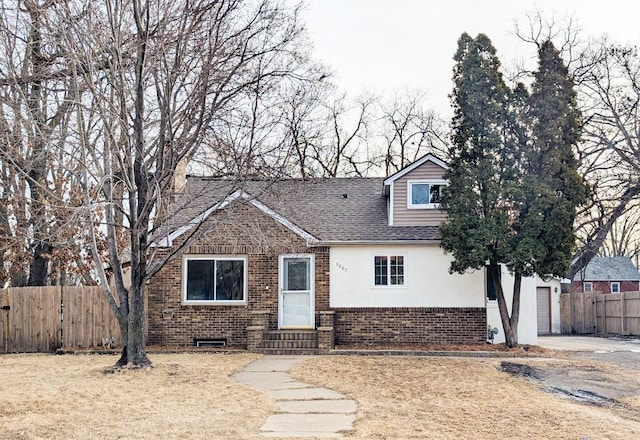 view of front facade with entry steps, fence, brick siding, and roof with shingles