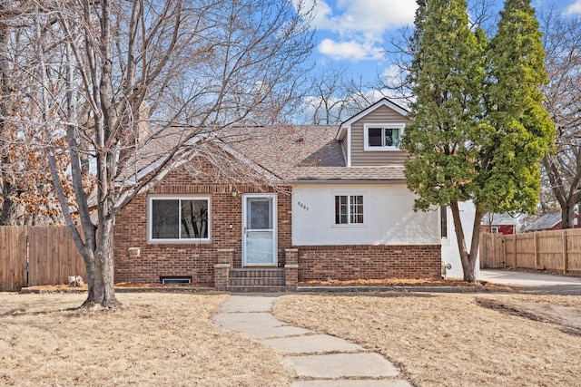 view of front facade featuring brick siding, fence, entry steps, roof with shingles, and stucco siding