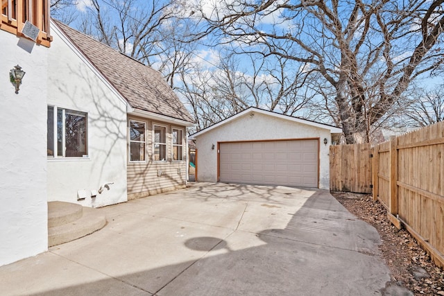 exterior space with an outbuilding, fence, a shingled roof, stucco siding, and a garage