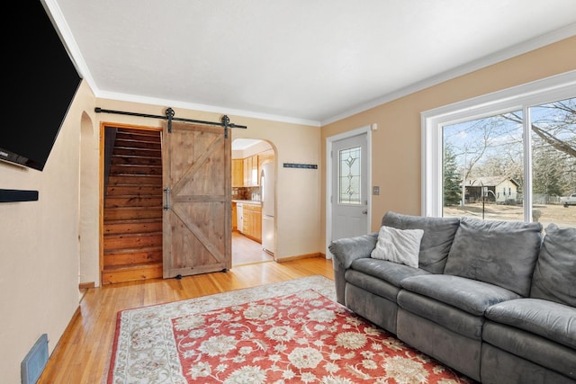 living room with arched walkways, visible vents, light wood finished floors, and ornamental molding