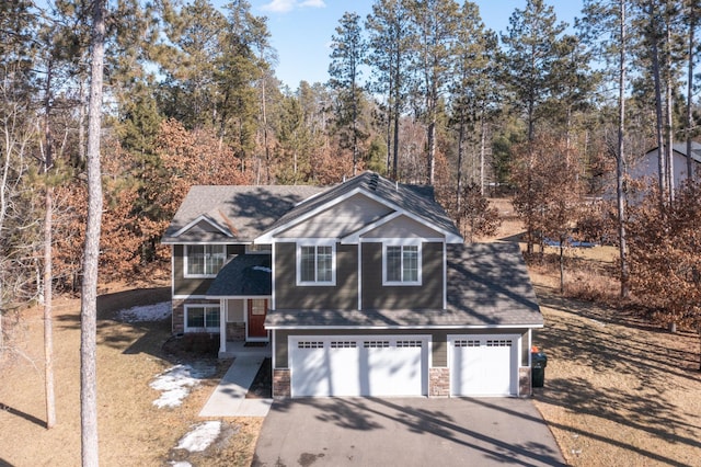 view of front of home featuring stone siding, driveway, and a garage