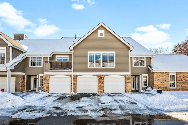 view of front of home with brick siding, a garage, and a balcony