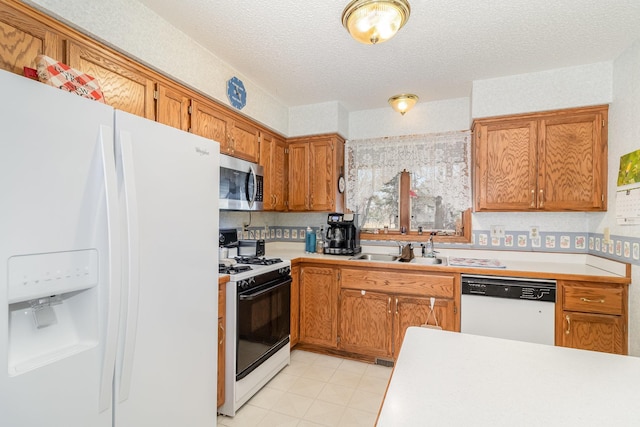 kitchen with light countertops, brown cabinetry, white appliances, a textured ceiling, and a sink