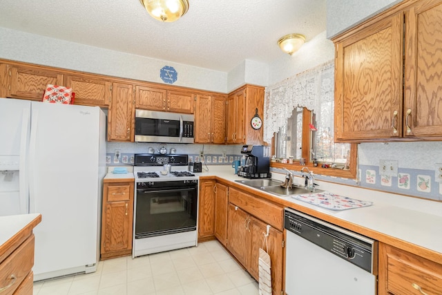 kitchen with light countertops, brown cabinetry, white appliances, a textured ceiling, and a sink