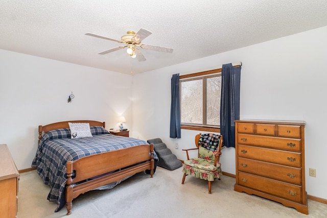 bedroom with a ceiling fan, light colored carpet, baseboards, and a textured ceiling