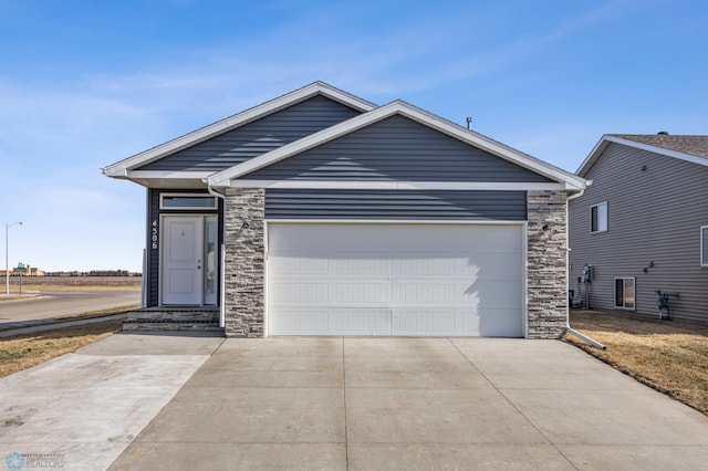 view of front of house featuring a garage, stone siding, and driveway