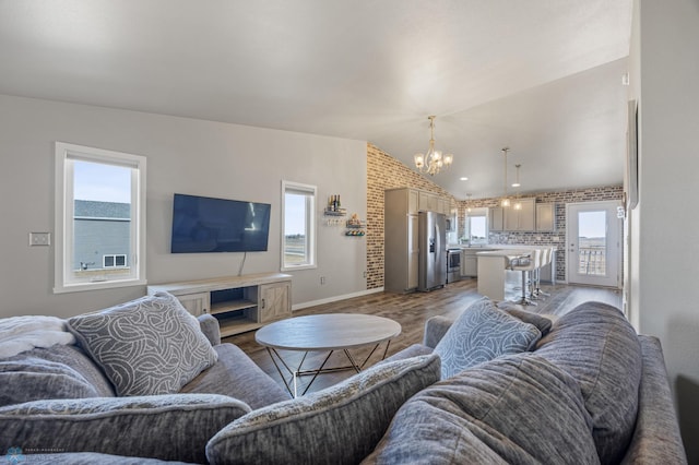 living area featuring a wealth of natural light, an inviting chandelier, wood finished floors, and vaulted ceiling