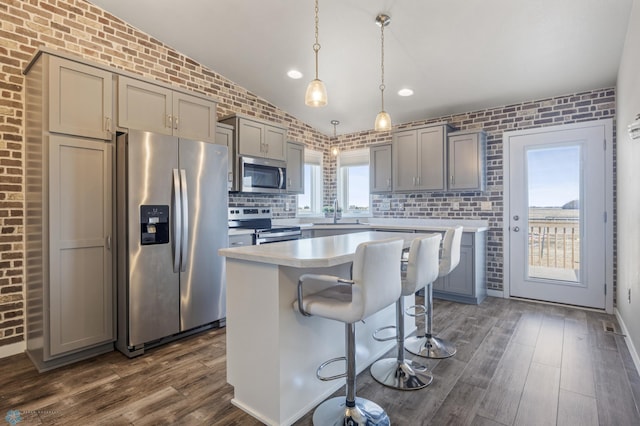 kitchen featuring brick wall, dark wood-type flooring, vaulted ceiling, gray cabinets, and stainless steel appliances