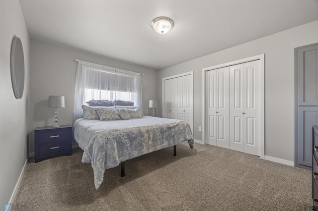 bedroom featuring dark carpet, baseboards, and two closets