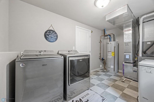 washroom with light floors, baseboards, laundry area, water heater, and washing machine and dryer