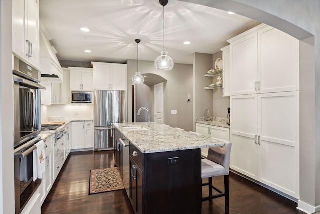 kitchen with a sink, arched walkways, appliances with stainless steel finishes, and white cabinets