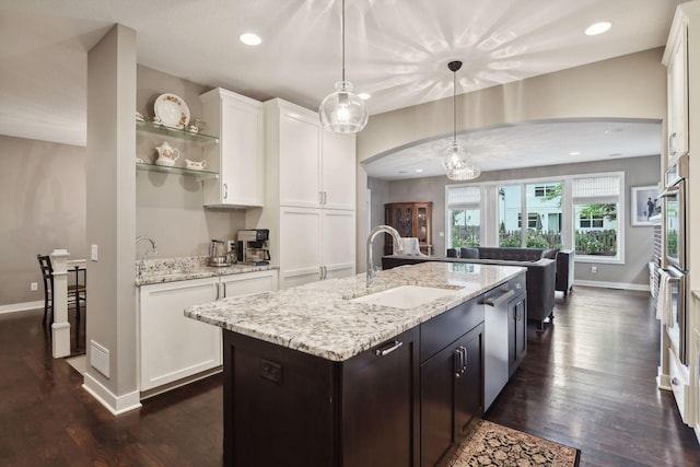 kitchen featuring a sink, baseboards, arched walkways, white cabinets, and dark wood-style flooring