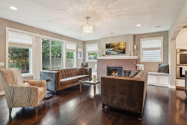 living area with recessed lighting, a textured ceiling, dark wood-style floors, and a fireplace