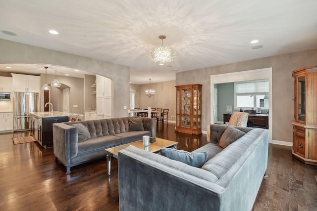 living room with dark wood-type flooring, recessed lighting, baseboards, and a chandelier