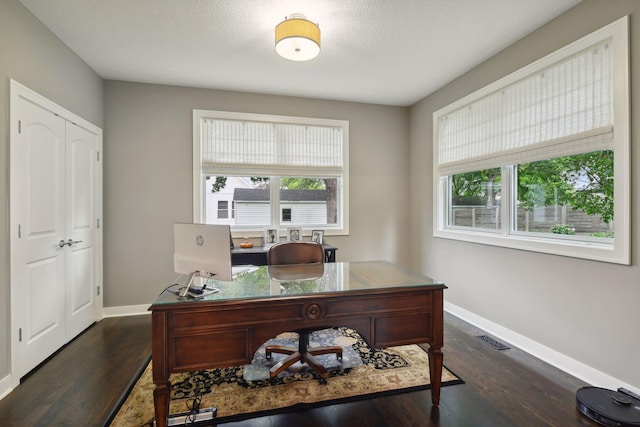 office with dark wood-style floors, a healthy amount of sunlight, and visible vents