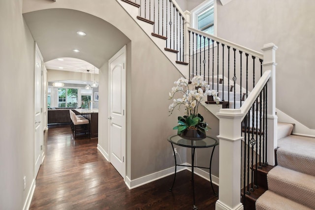 stairway featuring arched walkways, recessed lighting, baseboards, and wood finished floors