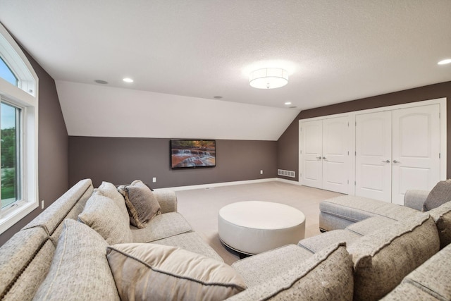 living area featuring visible vents, baseboards, light colored carpet, vaulted ceiling, and a textured ceiling