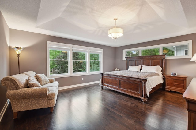 bedroom featuring a tray ceiling, baseboards, a textured ceiling, and dark wood finished floors