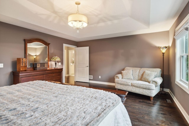 bedroom featuring dark wood finished floors, a raised ceiling, multiple windows, and baseboards