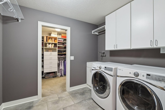 washroom with light tile patterned floors, cabinet space, a textured ceiling, and washing machine and dryer