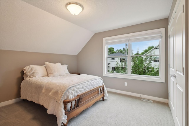 carpeted bedroom with vaulted ceiling, baseboards, and visible vents