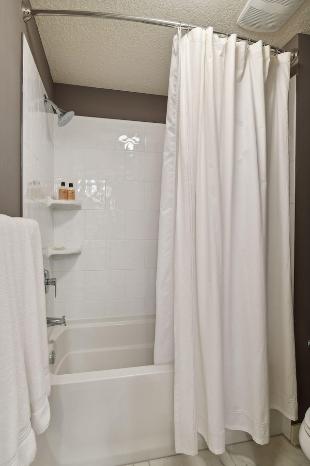 full bath featuring a textured ceiling and shower / tub combo