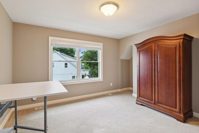 unfurnished office featuring visible vents, baseboards, light colored carpet, and a textured ceiling