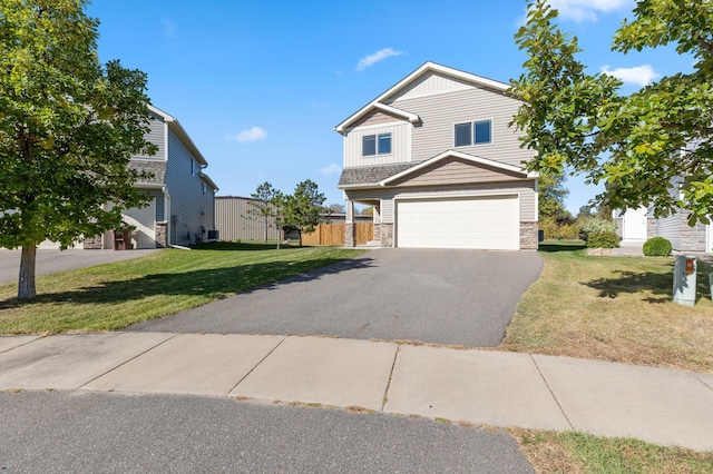 view of front of house with a front lawn, fence, aphalt driveway, a garage, and stone siding