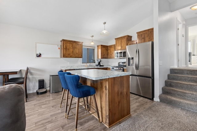 kitchen with a center island, stainless steel appliances, light wood-style floors, a breakfast bar area, and light countertops