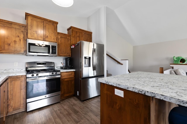 kitchen with light countertops, lofted ceiling, brown cabinets, appliances with stainless steel finishes, and dark wood-style flooring