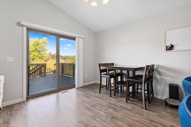 dining area featuring visible vents, wood finished floors, baseboards, and vaulted ceiling