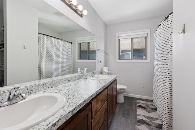 bathroom featuring toilet, wood finished floors, baseboards, and a sink