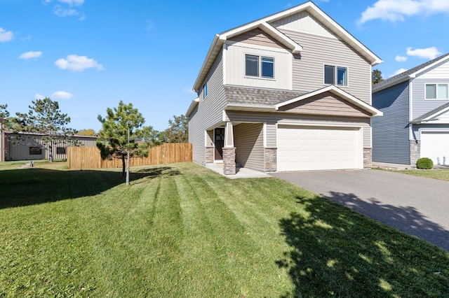 craftsman inspired home with aphalt driveway, stone siding, a front yard, and fence