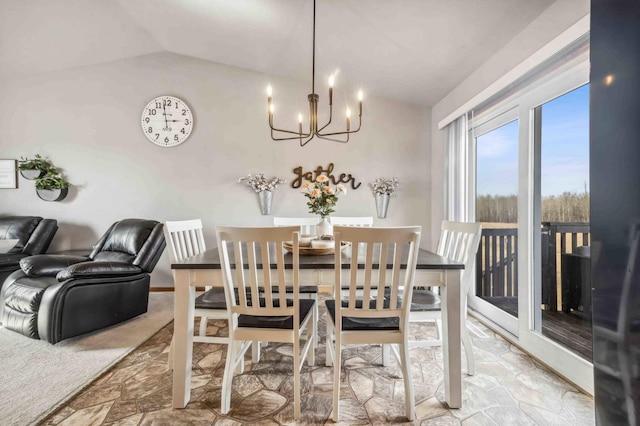 dining space featuring a chandelier, stone finish floor, and vaulted ceiling