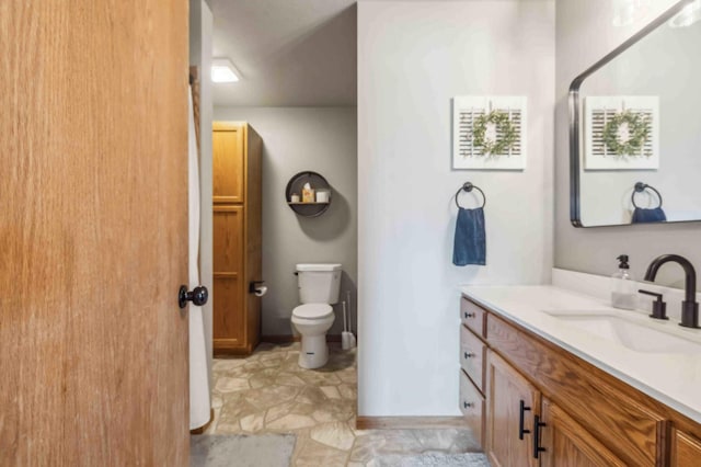 full bath featuring toilet, vanity, and baseboards