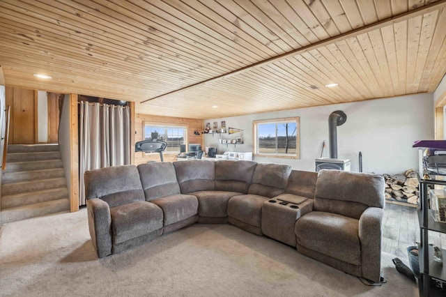 living area with stairway, a healthy amount of sunlight, wood ceiling, and a wood stove